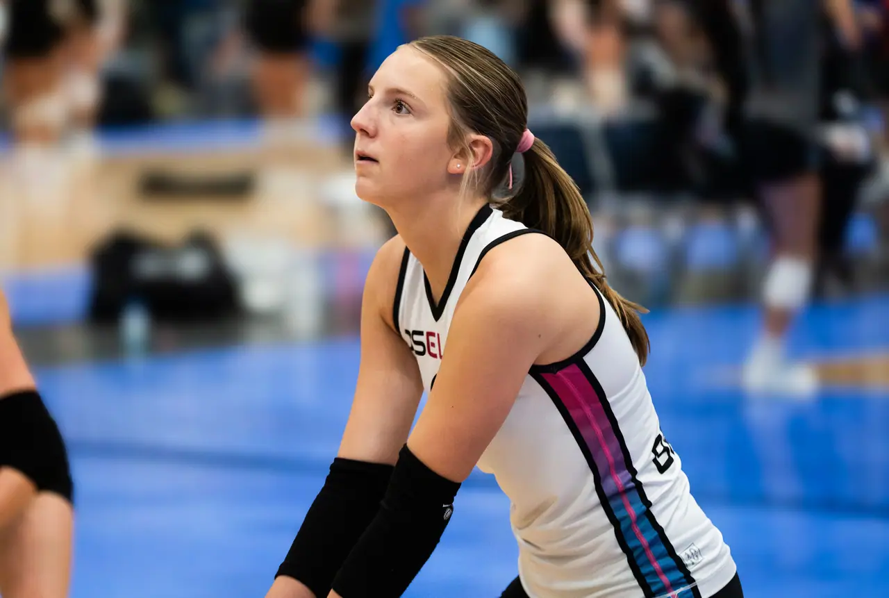 A DS Elite player in a white uniform in ready position, eyes locked on the ball